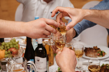group of male friends clink glasses with cognac and celebrate the holiday at a festive table