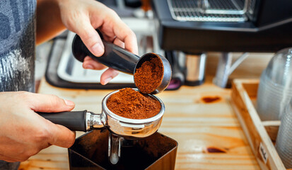 Barista pours coffee bean roaster powder ground coffee pouring into a portafilter with a barista...
