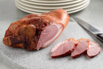 Traditional Croatian smoked pork knuckle and slices on a cutting board close up - obrazy, fototapety, plakaty