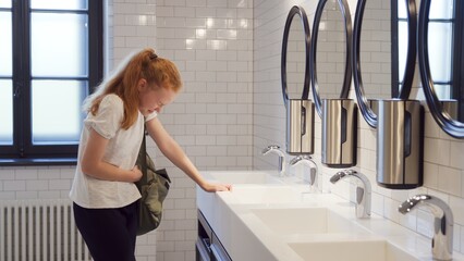 Teenage girl crying in school bathroom