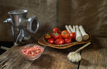 Meat grinder with food on a wooden table