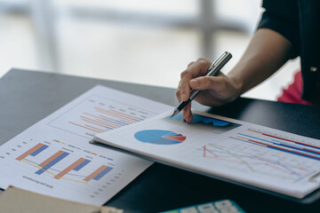 Close-up business concept of accountant holding graph document working on calculator to calculate financial data report Accounting documents and laptop computer at the office, close-up