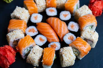 Sushi on the plate, lunch in the restaurant. Set of sushi roll with salmon, avocado, cream cheese, cucumber, rice, tuna on the black plate