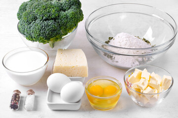 Ingredients for cooking broccoli tart with cheese on white table. Making savory shortbread pastry...