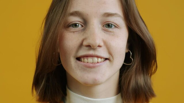 Close-up portrait of cheerful girl nodding head and smiling expressing agreement on yellow color background. People and emotions concept.