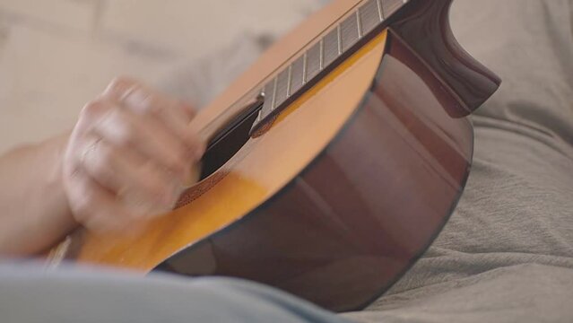 man rhythmically playing acoustic guitar