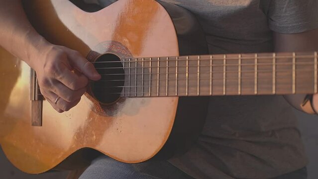 man rhythmically playing acoustic guitar