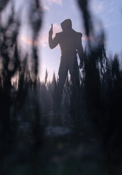 Man in hoodie holding pistol in a misty rural field at sunset. 3D render.