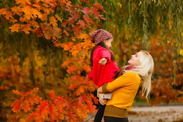 Fototapeta premium Hello autumn. smiling young mother and daughter in hat outdoors in the city park in autumn having fun time