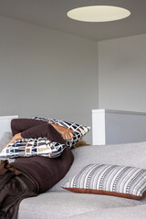 Charming middle-aged woman sitting on the sofa at home with a pillow on her face. She is depressed and lonely