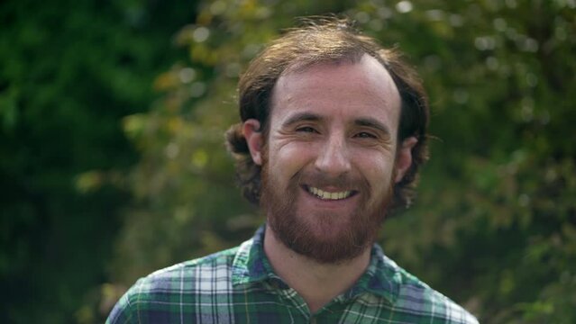 Happy man closeup face. Portrait of a redhead casual male person standing outdoors in nature