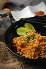 Pad Thai or Fried noodle Thai style, Thai style served with lime and seasonings. In a black palette, the visual style is dark tones.
