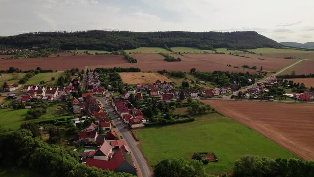 Aer ial view of a German village surrounded by meadows, farmland and forest in Germany.