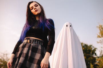 Young woman standing with ghost against blue sky outdoors during Halloween