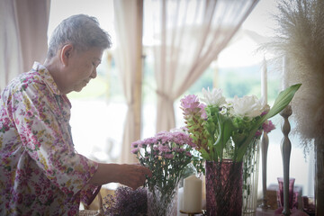 old woman decorate flower bouquet in vase on dining table