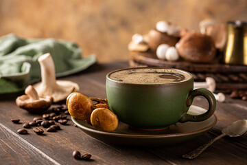 Mushroom coffee in green cup on wooden background. New Superfood trendy healthy concept with copy...
