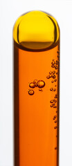 Yellow viscous liquid sunflower lecithin with bubbles in a transparent test tube on a white background
