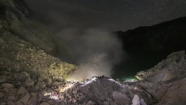 Tourist travelling in active volcano Kawah Ijen for looking blue flame and sulfur labor in the night sky at East Java, Indonesia