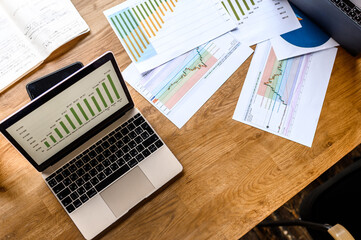 Working process Top view on graphs and charts on the table, laptop and phone nearby