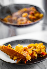 woman puts food from a frying pan into a plate