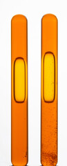 Yellow viscous liquid sunflower lecithin with bubbles in a transparent test tube on a white background