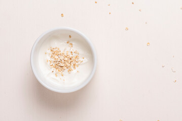 Bol blanco con yogurt y avena sobre fondo blanco, fotografía minimalista y clara. Desayuno...