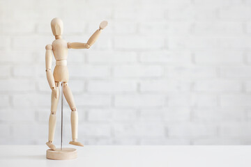 wooden human figure showing hello sign over white brick wall background - Powered by Adobe