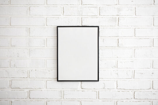 blank poster frame over white brick wall background