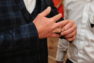 Hands of groom puts on a wedding gold ring on the wedding day