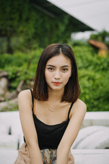 Beautiful female model, wearing a black tanktop, posing and stylish in the middle of a tennis court in the afternoon.