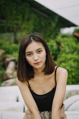 Beautiful female model, wearing a black tanktop, posing and stylish in the middle of a tennis court in the afternoon.