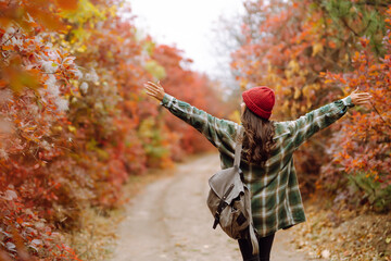 Beautiful woman taking pictures  in the autumn forest. Smiling woman enjoying autumn weather. Rest, relaxation, lifestyle concept.