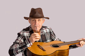Attractive old man with guitar and the typical infusion in Argentina and Uruguay called Mate