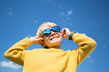 face of happy boy in sunglasses against sky. Color accent on yellow and blue colors of Ukrainian...