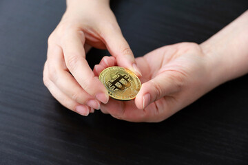 Bitcoin in female hands on dark wooden background. Electronic decentralized money, crypto currency