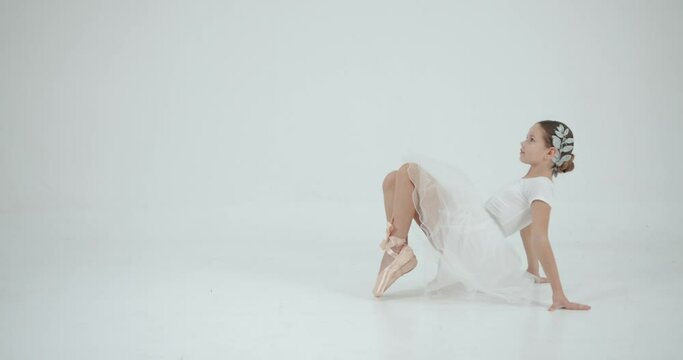 Little ballerina stretching and dancing on the white background