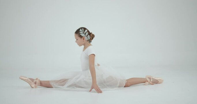Little ballerina stretching and dancing on the white background