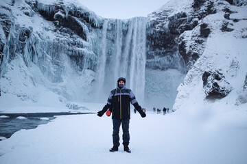 Fototapeta na wymiar happy young man in the middle of an icy waterfall in iceland