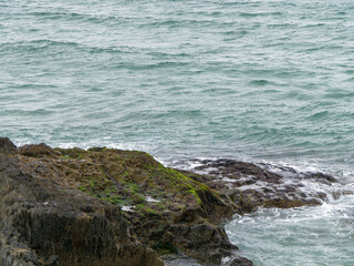 Fototapeta na wymiar Wild rock, landscape, rock formation beside body of water. Ocean waves & Coastal Cliffs