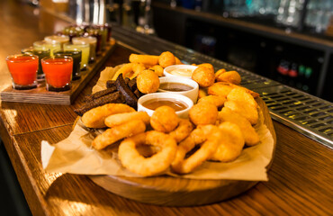 On the bar counter there is a set of various tinctures and a plate with snacks - onion rings, cheese sticks, balls and croutons