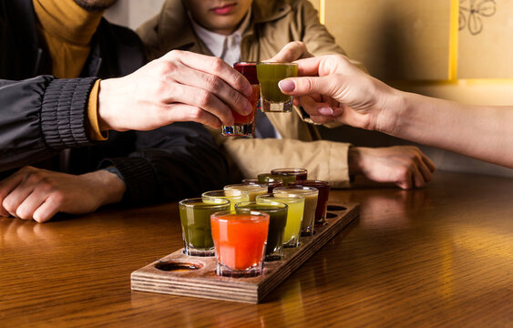 A group of friends clink glasses with tinctures at the table