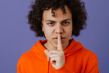 Fototapeta na wymiar Young curly man wearing hoodie showing silence gesture at camera