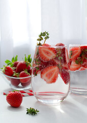 Detox strawberry thyme infused water or mocktail in a glass on white background
