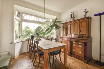 Simple table with chairs located under elegant chandelier near doors in stylish dining roome