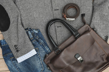 Top view blue jeans, leather bag and belt with grey tweed blazer. Casual business outlook. 