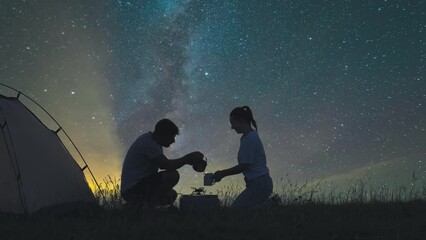 The two travelers preparing tea at the campsite on a starrying sky background - Powered by Adobe