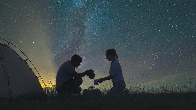 The two travelers preparing tea at the campsite on a starrying sky background