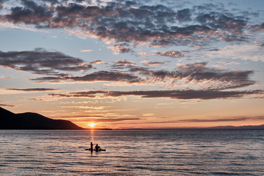 Barguzinsky Bay of Lake Baikal, Russia. Colorful sunset. Silhouette of couple on SUP-board.