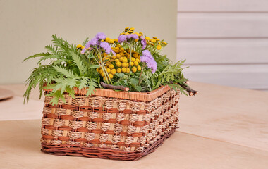 Bouquet of wild flowers and plants in rectangular wicker basket.