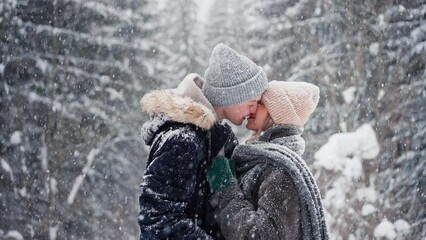 CLose-up of young couple hugging and kissing in winter under falling snow in nature. - Powered by Adobe
